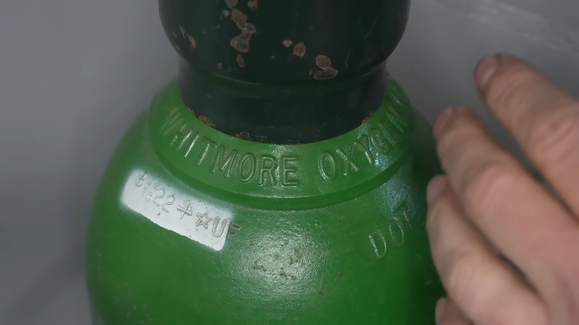 Gas cylinder markings showing inspection dates, pressure ratings, and neck ring ownership identification