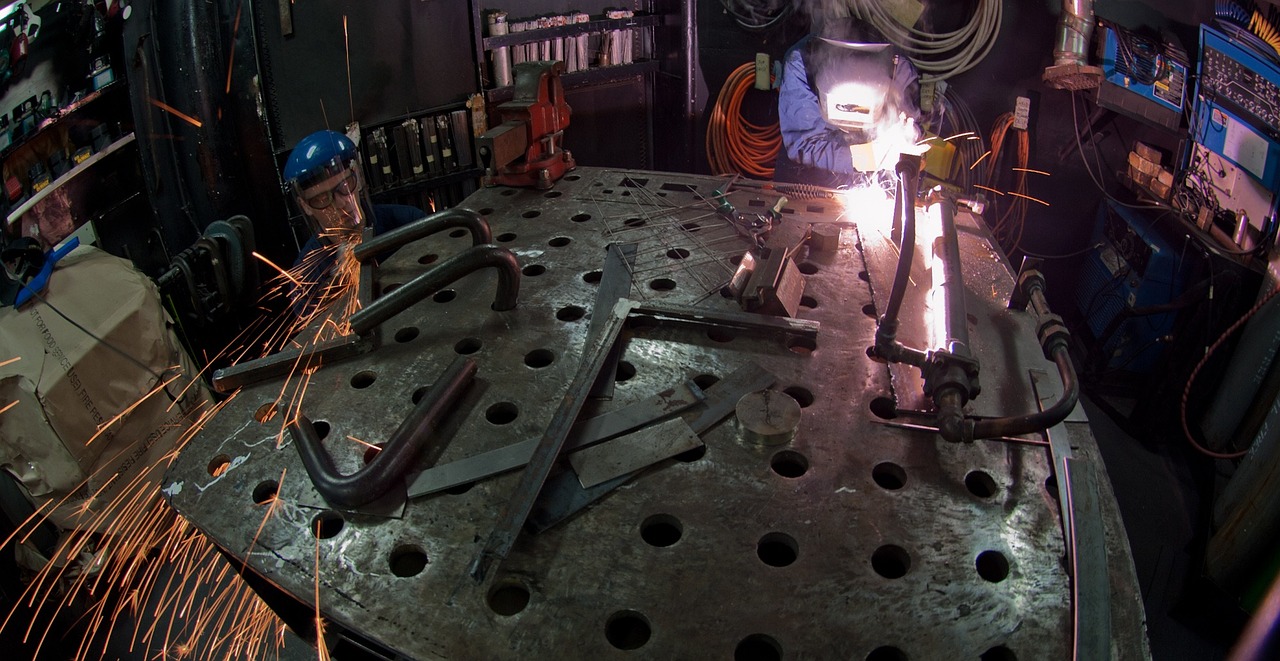 Professional welder performing arc welding with bright sparks showing proper heat input control